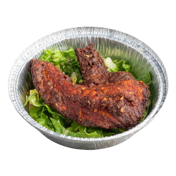 Two crispy, dark red chicken wings on a bed of green lettuce in a foil container.